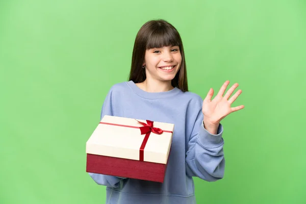 Little Girl Holding Gift Isolated Chroma Key Background Saluting Hand — Stock Photo, Image