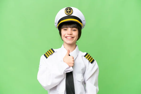 小女孩作为飞行员在孤立的彩色背景下举起大拇指做了一个手势 — 图库照片