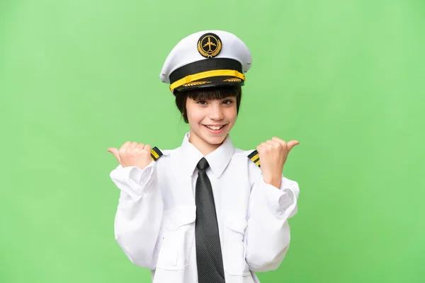 小女孩是飞机驾驶员 带着大拇指向上的手势和微笑 在孤立的彩色背景下驾驶飞机 — 图库照片