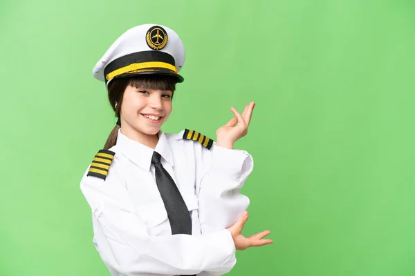小女孩作为飞机驾驶员 在孤立的彩色关键背景上向旁边伸出了手 以邀请她来 — 图库照片