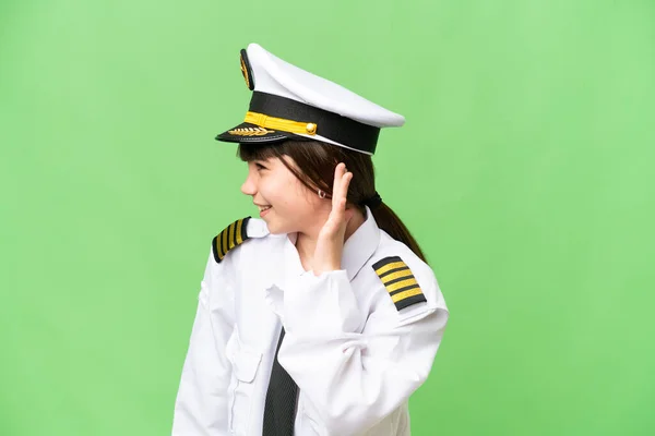 小女孩作为飞机驾驶员 在孤立的彩色关键背景下 用手捂住耳朵听着什么 — 图库照片