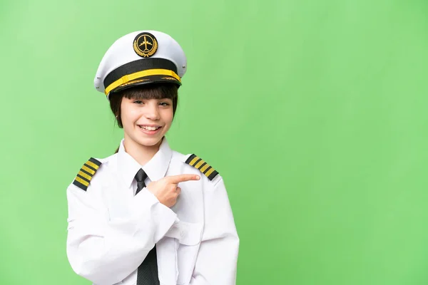 stock image Little girl as a Airplane pilot over isolated chroma key background pointing to the side to present a product