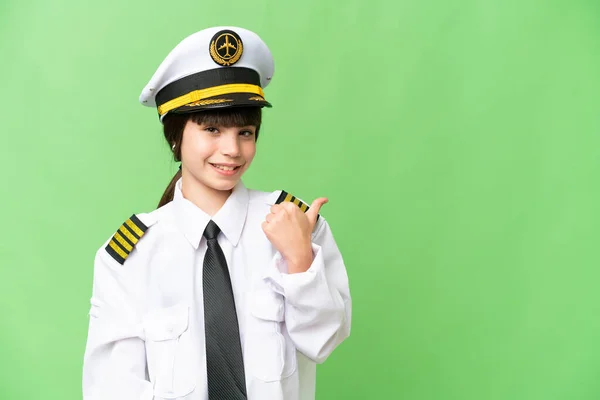 stock image Little girl as a Airplane pilot over isolated chroma key background pointing to the side to present a product