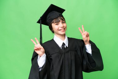 İzole edilmiş arka planda küçük bir üniversite kızı zafer işaretini iki eliyle gösteriyor.