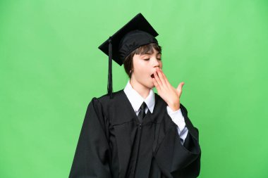 Küçük bir üniversiteli kız izole edilmiş arka planda esniyor ve ağzının ağzını eliyle kapatıyor.