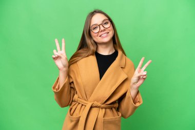 Genç sarışın kadın izole edilmiş krom anahtar arka planda iki eliyle zafer işareti gösteriyor.