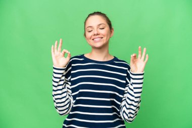 Zen pozunda izole edilmiş krom anahtar arka planı olan genç sarışın kadın.