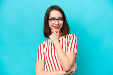 Genç Ukraynalı bir kadın mavi arka planda izole edilmiş, yana bakıyor ve gülümsüyor.