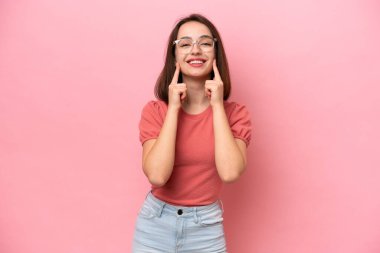 Pembe arka planda izole edilmiş genç Ukraynalı kadın mutlu ve hoş bir ifadeyle gülümsüyor.