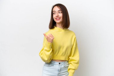 Beyaz arka planda izole edilmiş genç Ukraynalı kadın bir ürünü sunmak için kenarı işaret ediyor