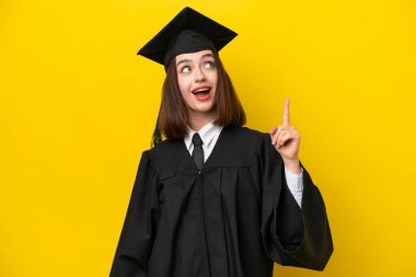 Genç üniversite mezunu Ukraynalı bir kadın sarı arka planda izole edilmiş ve şaşırmış.