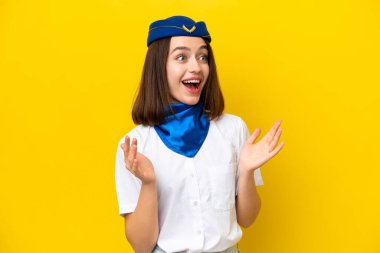 Uçak hostesi Ukraynalı kadın sarı arka planda şaşırmış bir yüz ifadesiyle izole edilmiş.