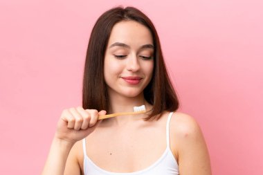 Genç Ukraynalı bir kadın pembe arka planda diş fırçasıyla izole edilmiş.