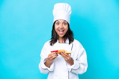 Mavi arka planda Sashimi tutan genç İspanyol aşçı kadın. Şaşırtıcı bir yüz ifadesi var.