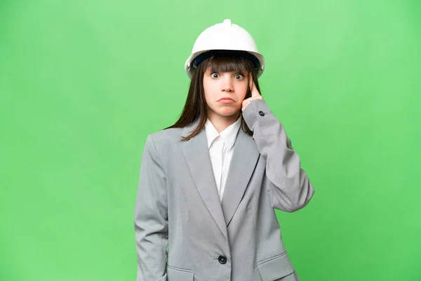 小女孩扮演一个戴着头盔的建筑师 在孤立的背景下拿着设计图 思考着一个想法 — 图库照片