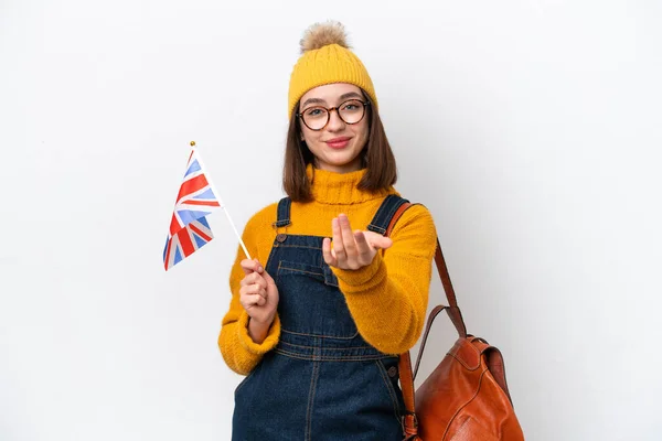 Young Ukrainian woman holding an United Kingdom flag isolated on white background inviting to come with hand. Happy that you came
