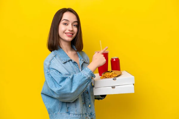 Young Ukrainian Woman Holding Fast Food Isolated Yellow Background Pointing — Stock Photo, Image