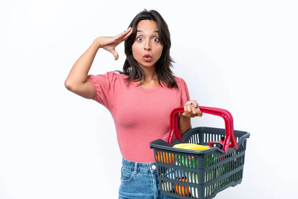 驚きの表情で食べ物でいっぱいの買い物かごを持っている若い女性 — ストック写真