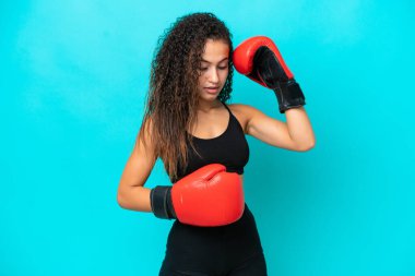 Genç Arap kadın mavi arka planda boks eldivenleriyle izole edilmiş.