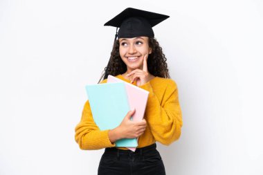 Arap üniversitesinden mezun bir kadın elinde beyaz arka planda kitap tutarken bir yandan bakıp bir yandan da