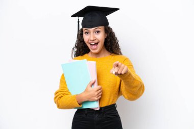 Arap üniversitesinden mezun bir kadın elinde beyaz arka planda kitap tutuyor. Şaşırmış ve ön tarafı işaret ediyor.