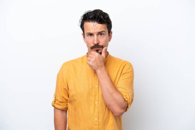 Bıyıklı genç bir adam beyaz arka planda izole edilmiş düşünüyor.