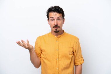 Bıyıklı genç adam beyaz arka planda şüpheli hareketler yapıyor.