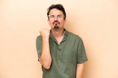 Beyazlı genç bir adam bej arka planda izole edilmiş, mutsuz bir ifadeyle.