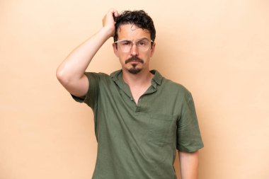 Beyazlı genç bir adam bej arka planda izole edilmiş ve hayal kırıklığı ifadesi var.