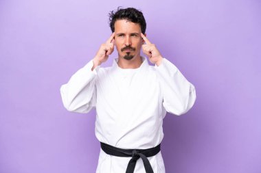 Mor arka planda karate yapan genç beyaz adamın şüpheleri ve düşünceleri var.
