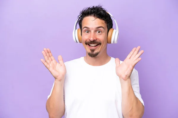 Young Caucasian Man Isolated Purple Background Surprised Listening Music — Stock Photo, Image