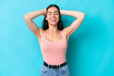 Mavi arka planda izole edilmiş genç beyaz kadın gülüyor.