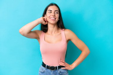 Mavi arka planda izole edilmiş genç beyaz kadın gülüyor.