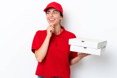 Pizza teslimatı, beyaz arka planda izole edilmiş pizza kutularını alan, beyaz üniformalı beyaz bir kadın yan tarafa bakıyor ve gülümsüyor.