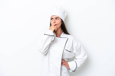 Beyaz arka planda genç bir aşçı kadın. Şüpheleri var ve kafası karışmış bir yüz ifadesi var.