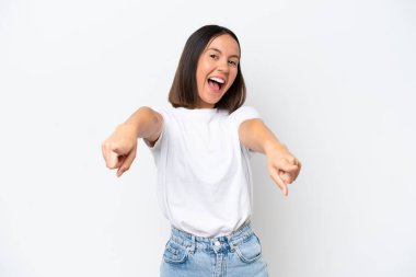 Beyaz arka planda izole edilmiş genç beyaz kadın şaşırmış ve ön tarafı işaret ediyor.