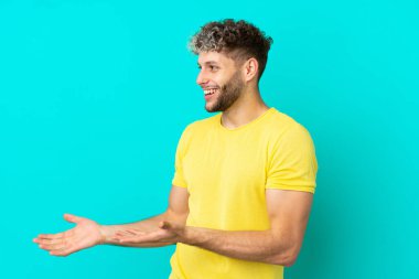 Mavi arka planda mahsur kalmış yakışıklı, beyaz bir adam.