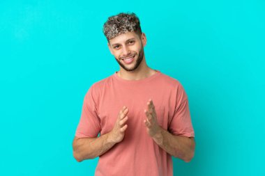 Mavi arka planda izole edilmiş yakışıklı beyaz adam bir konferansın sunumundan sonra alkışlıyor.