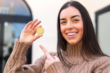 Elinde Bitcoin tutan genç bir kadın.