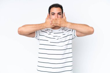 Beyaz arka planda izole edilmiş genç beyaz bir adam elleriyle ağzını kapatıyor.