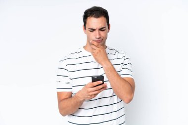 Beyaz arka planda izole edilmiş genç beyaz bir adam düşünüyor ve bir mesaj gönderiyor.