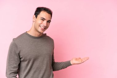 Pembe arka planda izole edilmiş genç beyaz adam gülümserken bir fikir sunuyor.