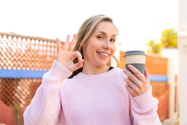 Mladá Blondýnka Žena Drží Odnést Kávu Venku Ukazuje Znamení Prsty — Stock fotografie