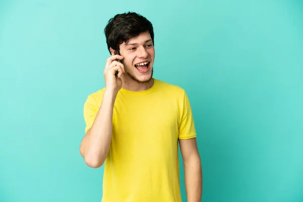 Молодий Російський Чоловік Ізольований Синьому Тлі Веде Розмову Мобільним Телефоном — стокове фото