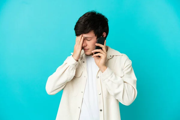 Młody Rosjanin Korzystający Telefonu Komórkowego Niebieskim Tle Zmęczonym Chorym Wyrazem — Zdjęcie stockowe