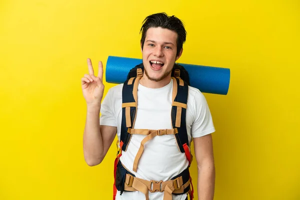 Młody Alpinista Rosyjski Człowiek Dużym Plecakiem Odizolowany Żółtym Tle Uśmiecha — Zdjęcie stockowe