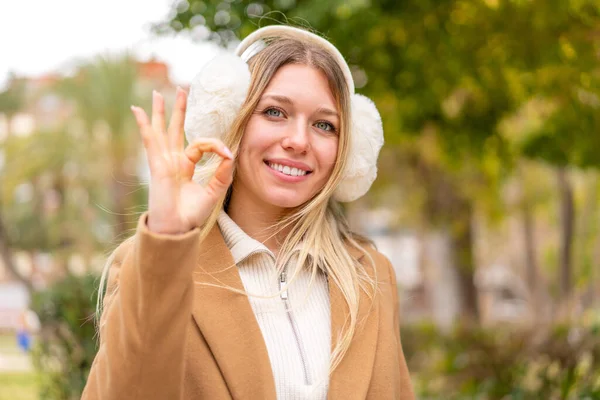 Młoda Ładna Blondynka Kobieta Nosić Zimowe Mufy Zewnątrz Pokazując Znak — Zdjęcie stockowe
