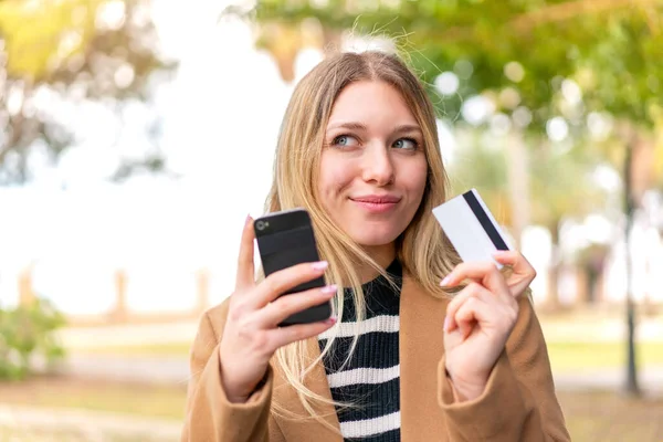 Молодая Красивая Блондинка Улице Покупает Мобильного Помощью Кредитной Карты — стоковое фото