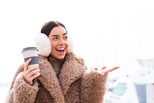 Młoda Kobieta Ubrana Zimowe Kajdanki Trzymająca Kawę Świeżym Powietrzu Zaskakującym — Zdjęcie stockowe