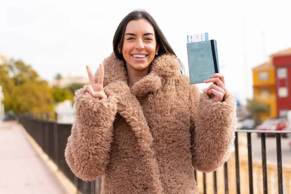 Jonge Vrouw Met Een Paspoort Buitenlucht Glimlachend Met Een Overwinningsteken — Stockfoto